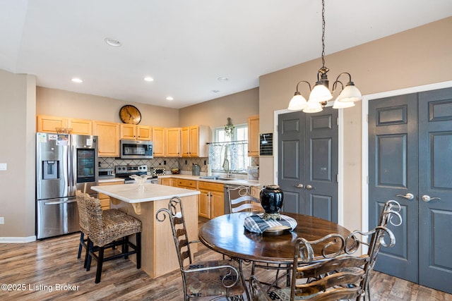 kitchen with a center island, pendant lighting, stainless steel appliances, light countertops, and a sink