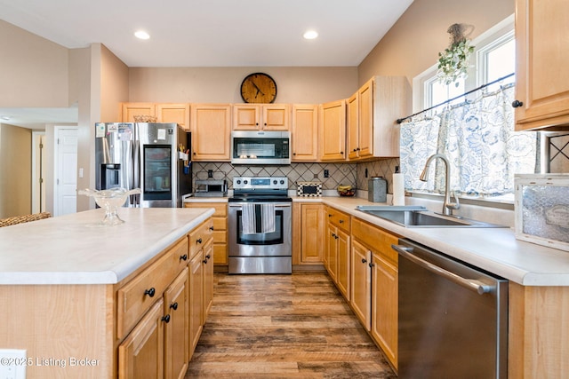 kitchen with stainless steel appliances, light countertops, backsplash, a sink, and wood finished floors