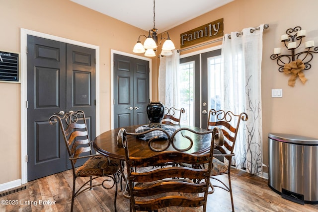 dining space with baseboards, visible vents, a chandelier, and wood finished floors