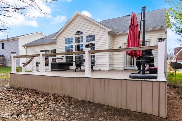 rear view of property featuring a shingled roof and a wooden deck