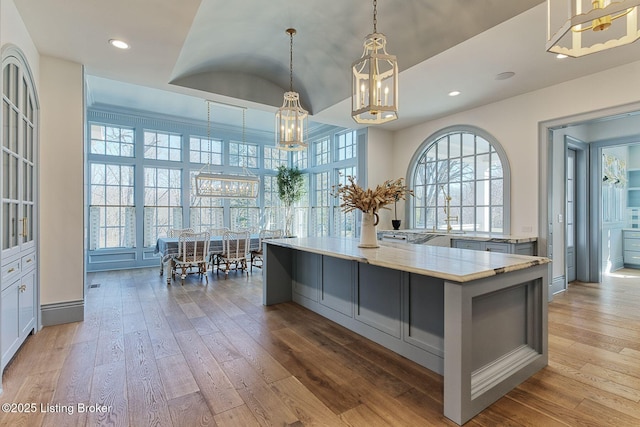 kitchen with light stone counters, recessed lighting, hanging light fixtures, a large island, and light wood-type flooring