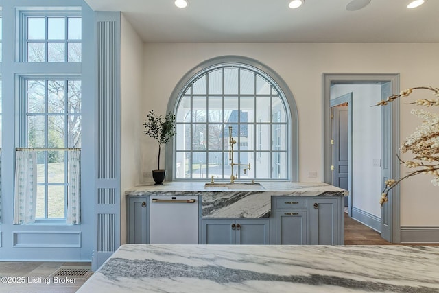 kitchen with plenty of natural light, dishwasher, and light stone countertops