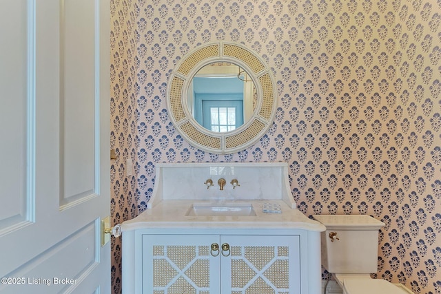 bathroom featuring vanity, toilet, and wallpapered walls