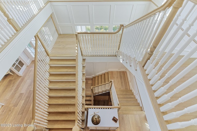 staircase featuring a decorative wall and wood finished floors