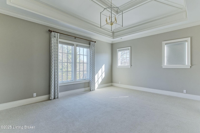 carpeted spare room featuring an inviting chandelier, baseboards, a raised ceiling, and crown molding