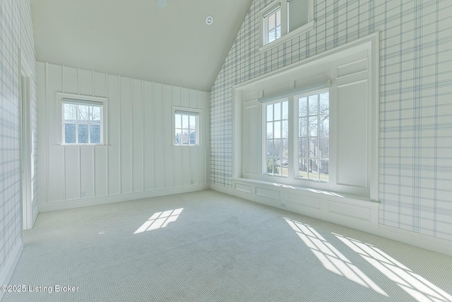 empty room featuring wallpapered walls, carpet, high vaulted ceiling, and baseboards