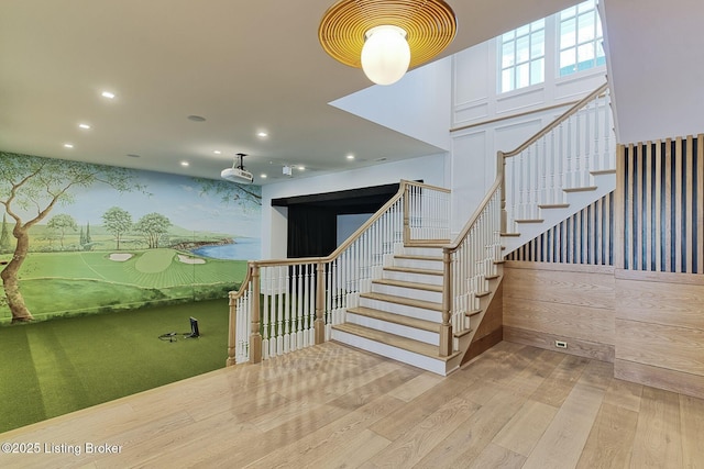 staircase with an accent wall, recessed lighting, hardwood / wood-style flooring, and wallpapered walls