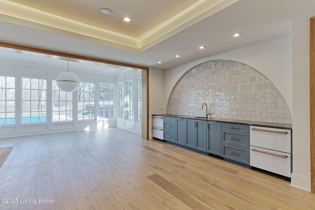 bar with light wood-style floors, decorative backsplash, a sink, and recessed lighting