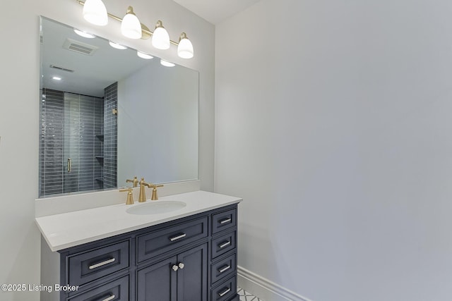 bathroom with visible vents, a tile shower, vanity, and baseboards