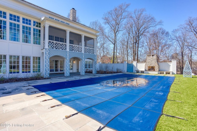 view of swimming pool with a fenced in pool, a patio, fence, french doors, and an outdoor stone fireplace