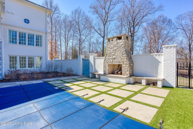 view of patio featuring an outdoor stone fireplace and fence