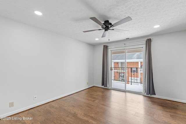 empty room featuring visible vents, a textured ceiling, baseboards, and wood finished floors