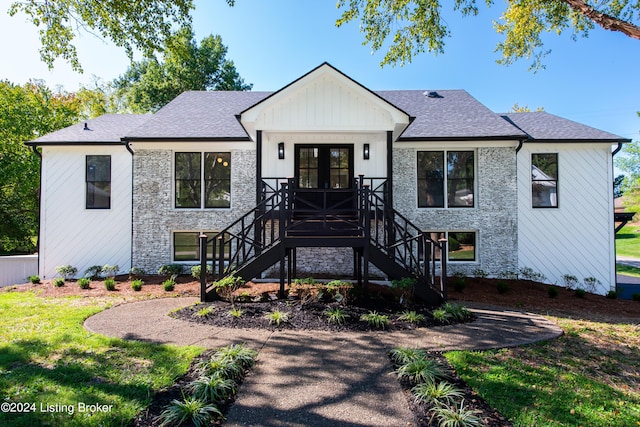 modern farmhouse style home with a shingled roof, french doors, stone siding, and stairs