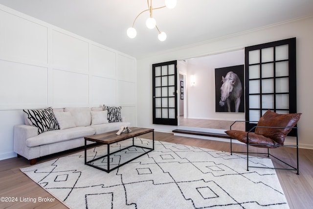 living room with light wood-style floors, a decorative wall, baseboards, and ornamental molding