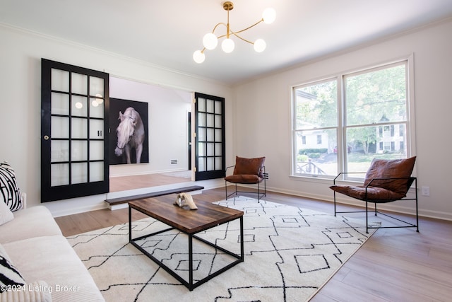 living room with light wood-type flooring, baseboards, ornamental molding, and a chandelier