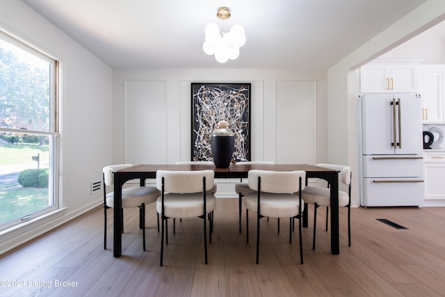 dining space with a wealth of natural light, visible vents, a notable chandelier, and light wood finished floors