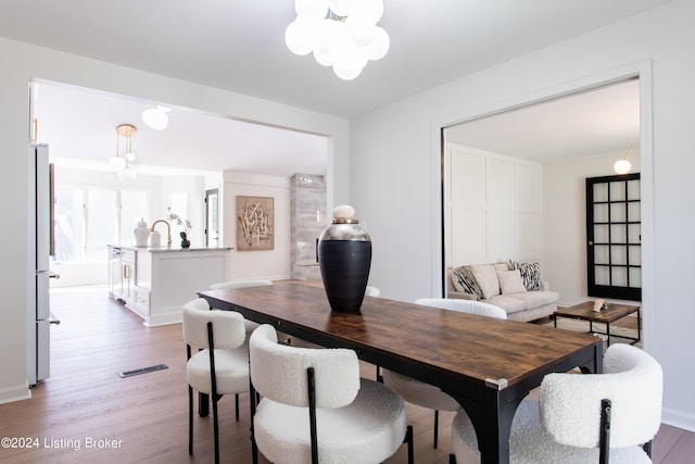 dining space with light wood-style flooring, visible vents, and a chandelier