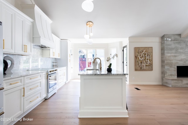 kitchen featuring white cabinetry, a center island with sink, a sink, and white range with electric cooktop