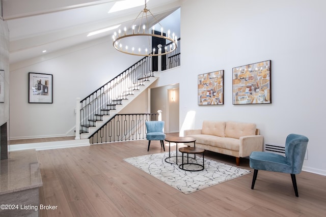 living room featuring stairway, baseboards, a notable chandelier, and wood finished floors