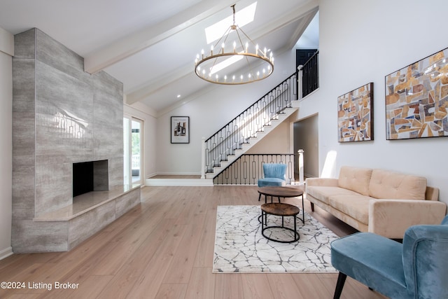 living room with a chandelier, a premium fireplace, wood finished floors, stairs, and beamed ceiling