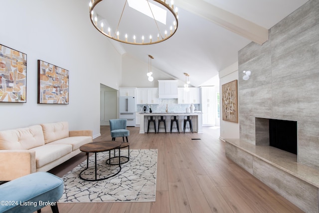 living room featuring a chandelier, high vaulted ceiling, a premium fireplace, light wood-style floors, and beamed ceiling