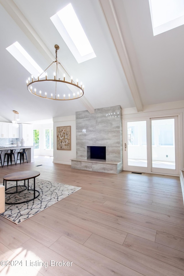 living room featuring a skylight, visible vents, light wood-style flooring, beamed ceiling, and an inviting chandelier