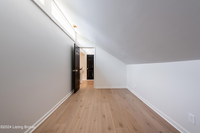 additional living space featuring lofted ceiling, light wood finished floors, and baseboards