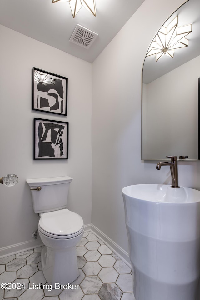 half bathroom with toilet, visible vents, and baseboards