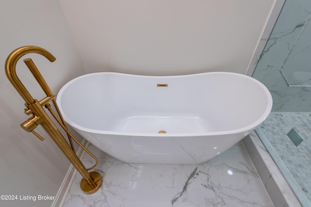 full bath with marble finish floor and a freestanding tub