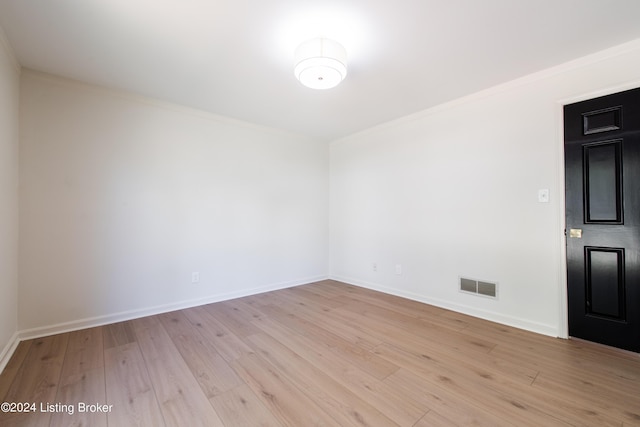 empty room with ornamental molding, visible vents, light wood-style flooring, and baseboards