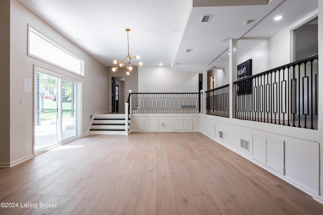 spare room with stairway, visible vents, a notable chandelier, and light wood-style flooring