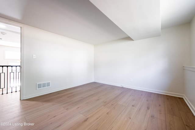 spare room featuring light wood-style flooring, visible vents, and baseboards