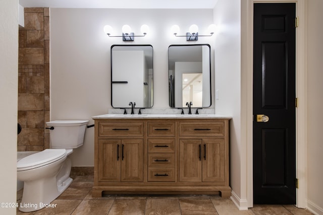 full bath with double vanity, a sink, toilet, and baseboards