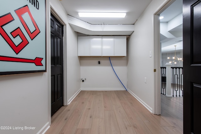 corridor with a chandelier, light wood-style flooring, and baseboards