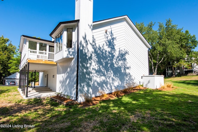 view of side of property featuring a sunroom, a chimney, and a yard