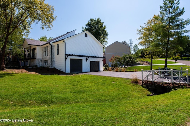 view of side of home with a yard, aphalt driveway, and an attached garage