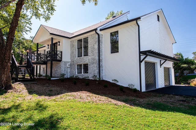 view of home's exterior with a yard, stairway, a garage, stone siding, and a wooden deck