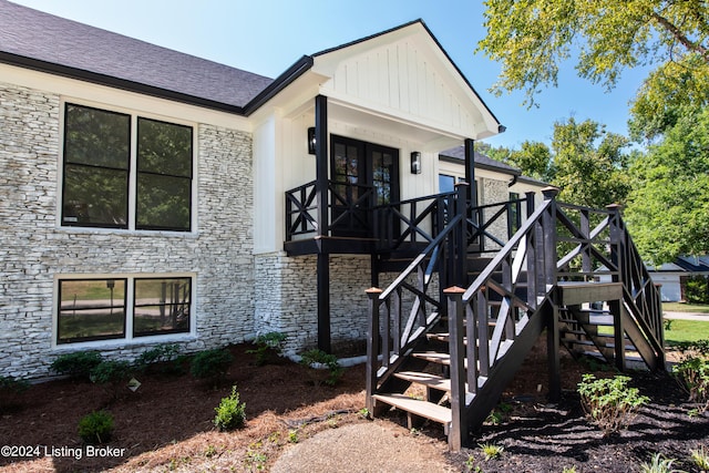 exterior space with board and batten siding, roof with shingles, and stairway