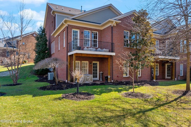 view of front of home with a balcony, brick siding, cooling unit, and a front yard