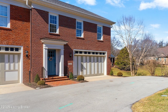 view of front facade with a garage, brick siding, and driveway