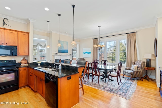 kitchen featuring black appliances, a kitchen bar, open floor plan, and a sink