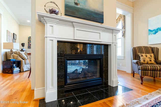 details featuring crown molding, a fireplace, baseboards, and wood finished floors