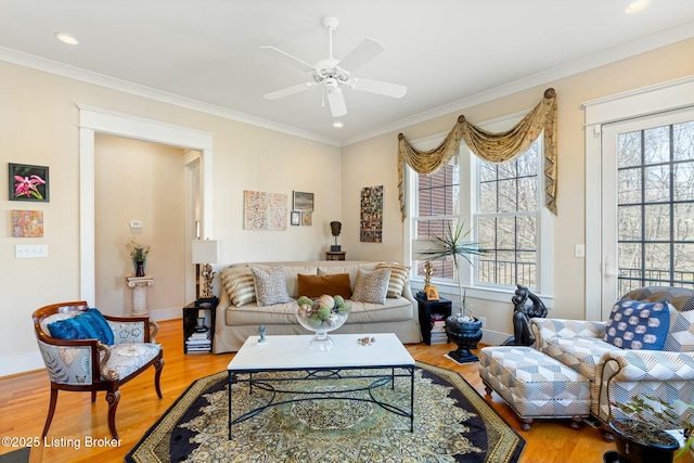 living area featuring a healthy amount of sunlight, crown molding, and wood finished floors