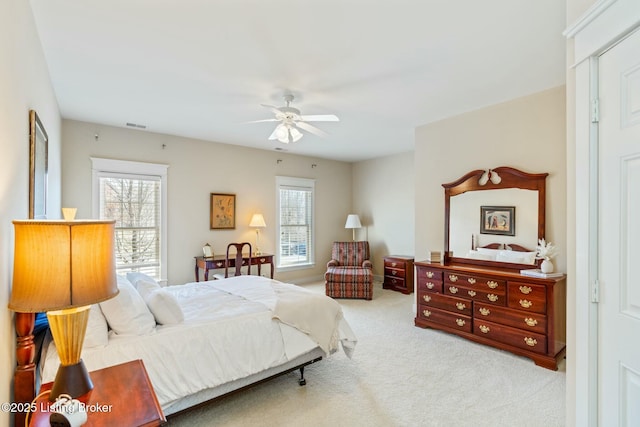 carpeted bedroom with visible vents, multiple windows, and a ceiling fan