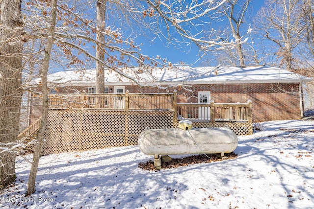 snow covered property with a deck and brick siding