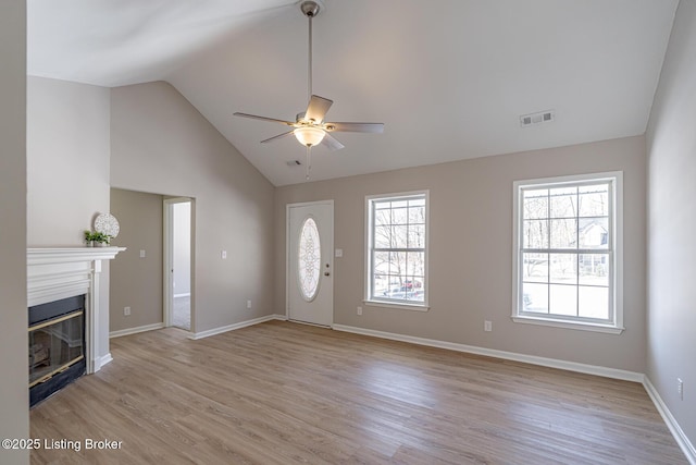 entryway featuring ceiling fan, visible vents, baseboards, light wood-style floors, and a glass covered fireplace