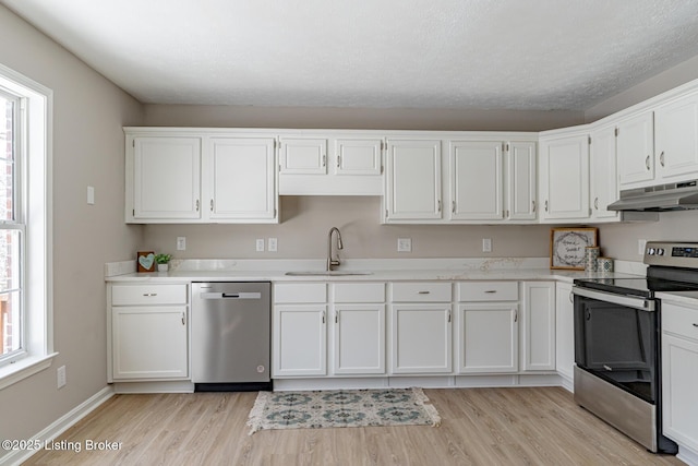 kitchen featuring appliances with stainless steel finishes, white cabinets, light countertops, and under cabinet range hood