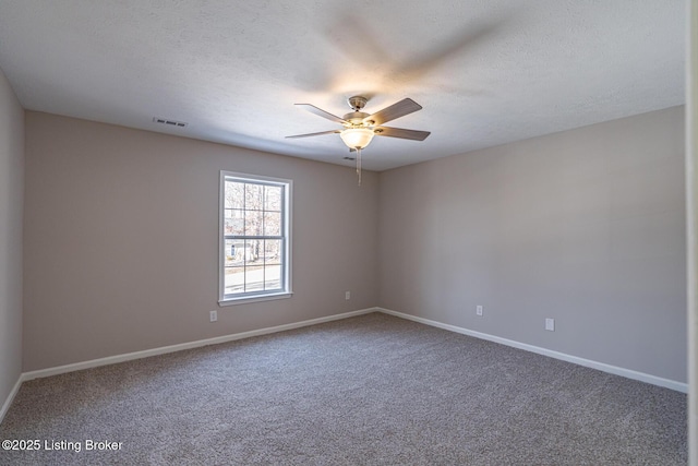 carpeted spare room featuring a textured ceiling, visible vents, a ceiling fan, and baseboards