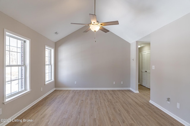 empty room with visible vents, vaulted ceiling, ceiling fan, light wood-type flooring, and baseboards