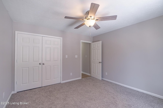 unfurnished bedroom with a textured ceiling, carpet flooring, a ceiling fan, baseboards, and a closet